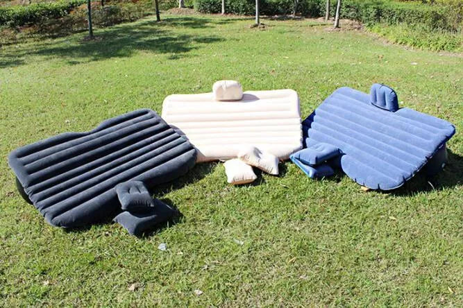 Black inflatable car bed with flocked texture and two pillows, shown inside a car boot.