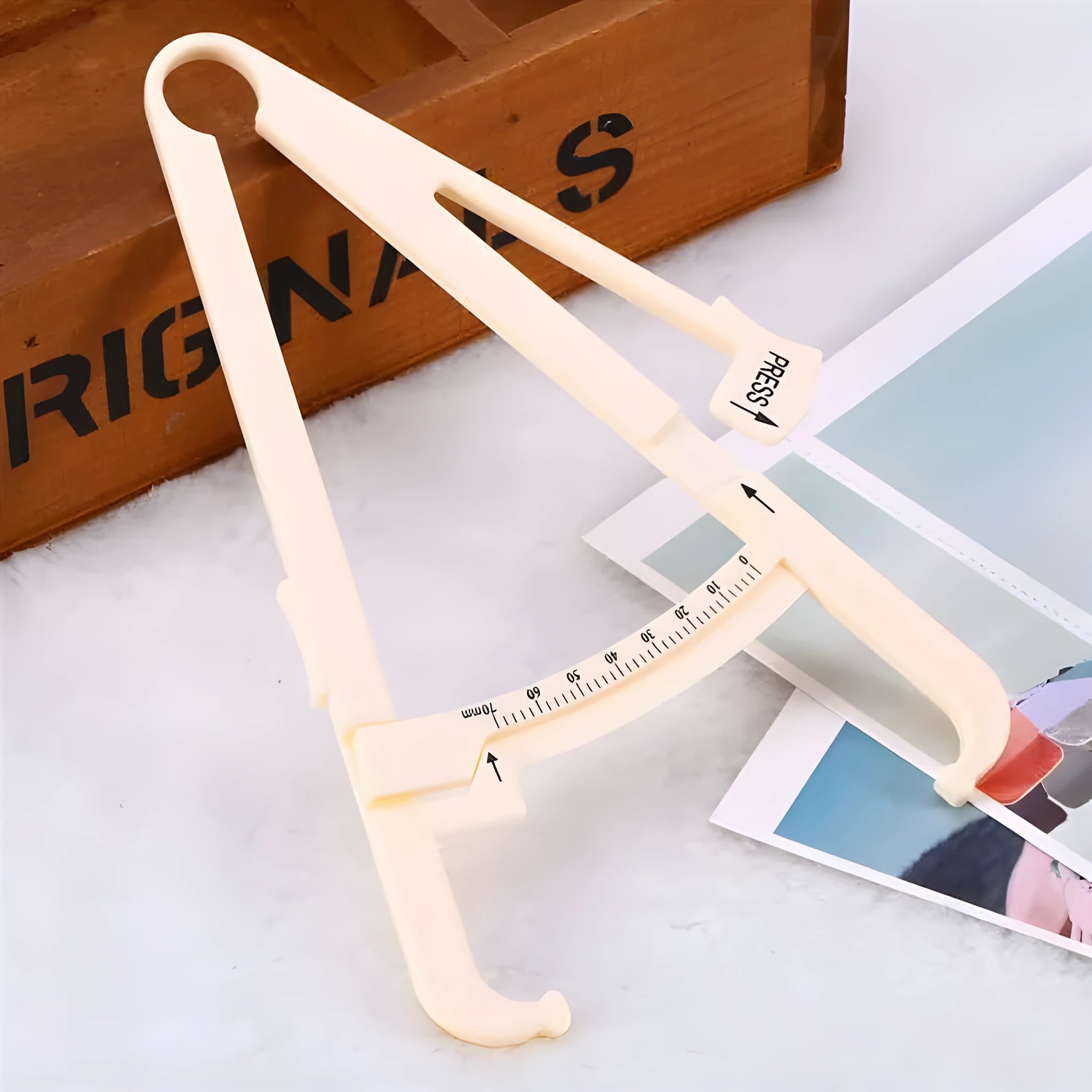 Clear acrylic body fat caliper showing measurement scale up to 200mm with sebum clamp design