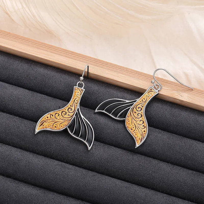 Women's retro-style fishtail-shaped alloy earrings with a whale decoration in white gold colour.