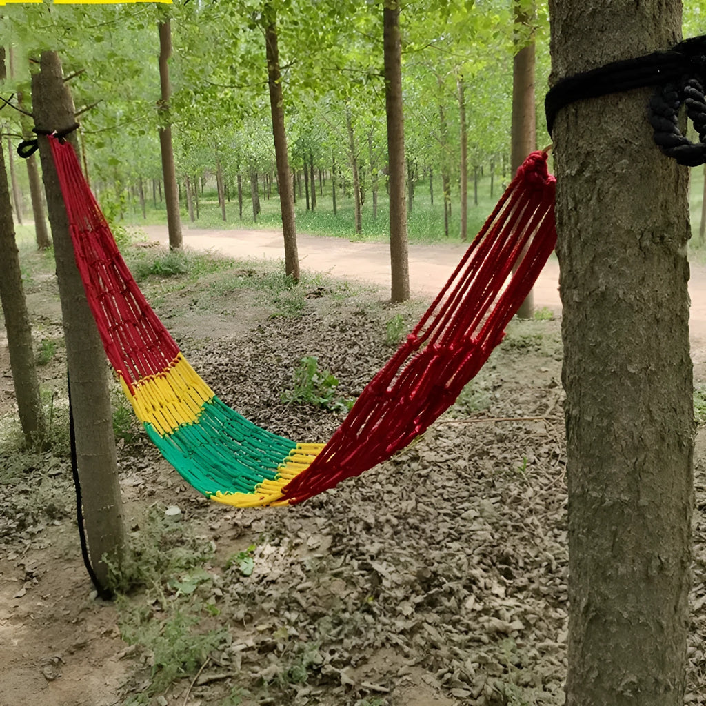 Outdoor nylon rope mesh hammock hung between two trees showing its woven construction and included tying ropes.