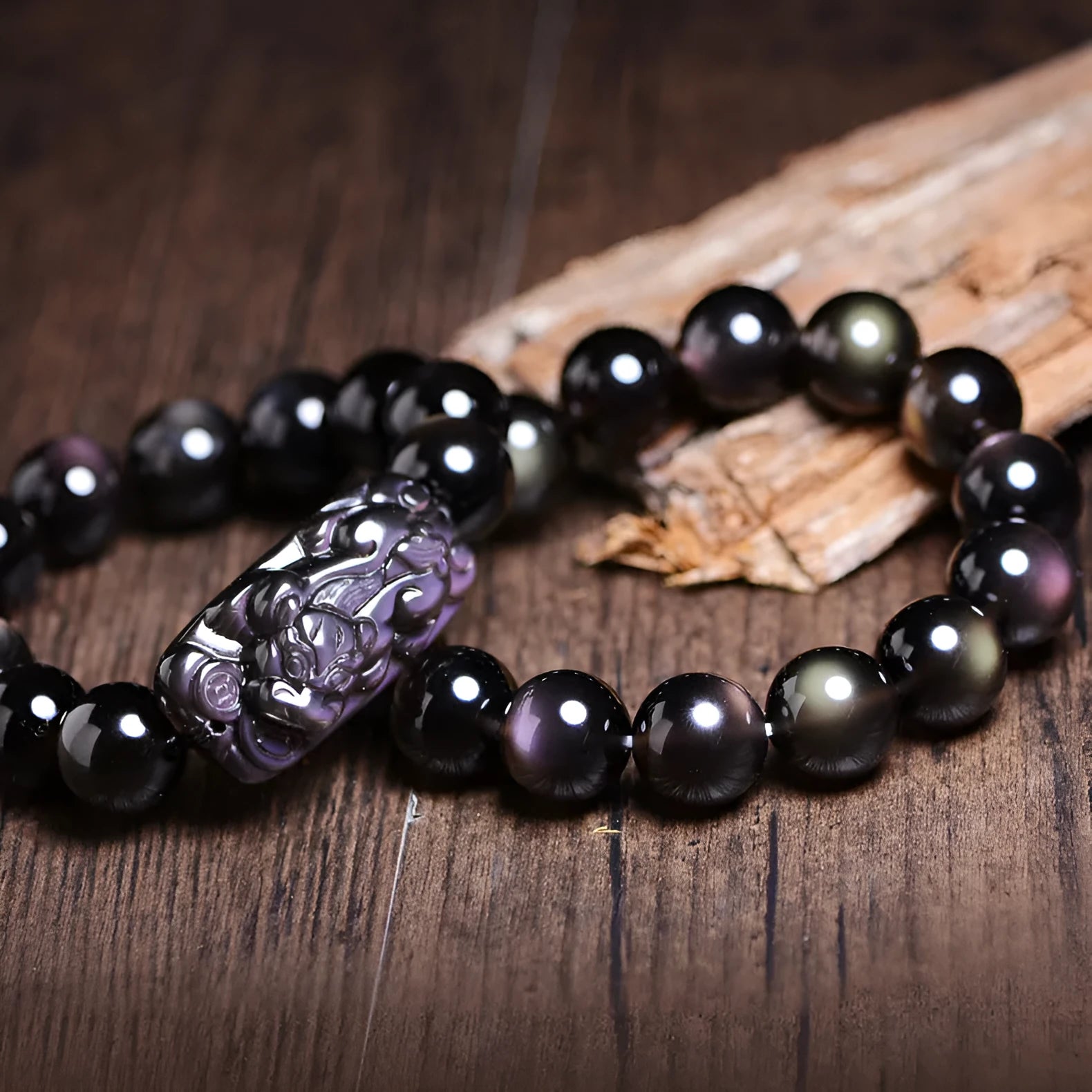 Polished icy obsidian crystal Pi Xiu bracelet with geometric beads on a white background.
