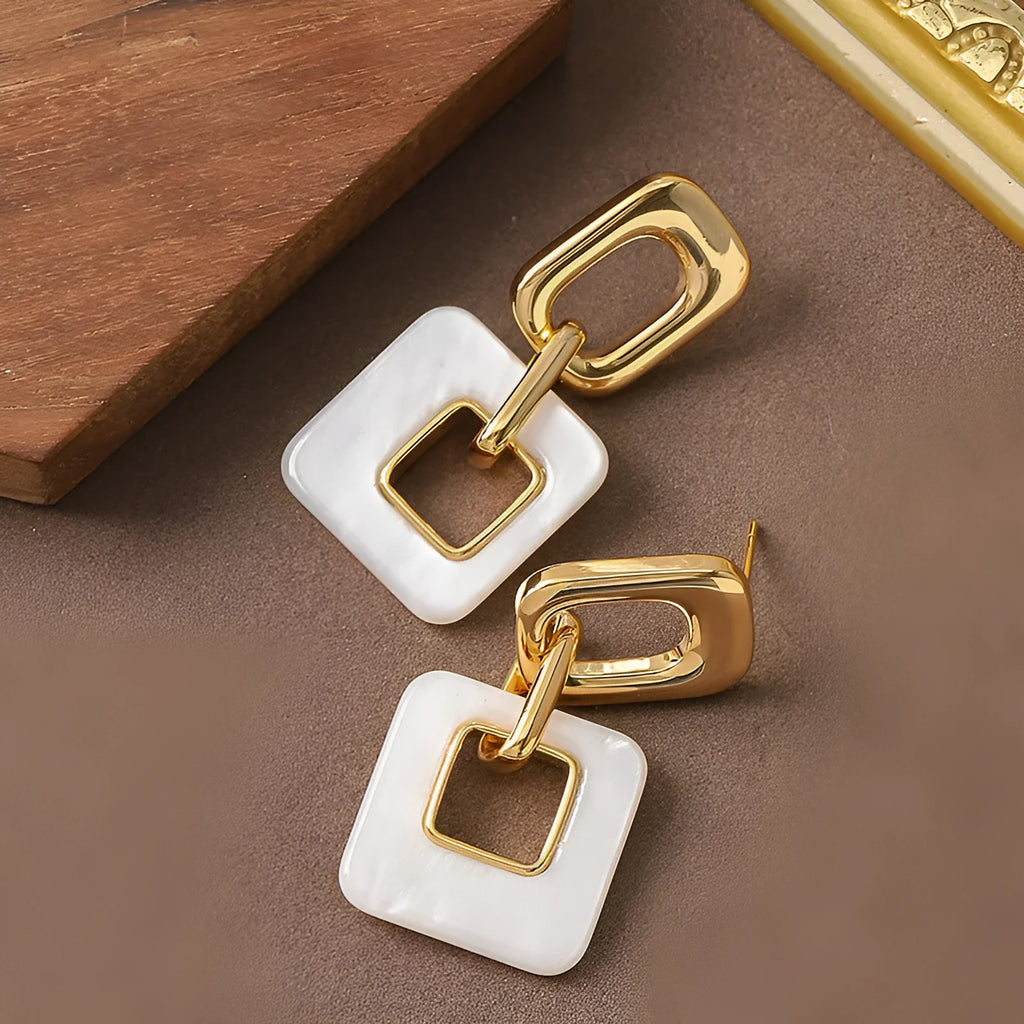 Pair of hollow geometric square copper earrings with chamfered corners in silver tone finish.