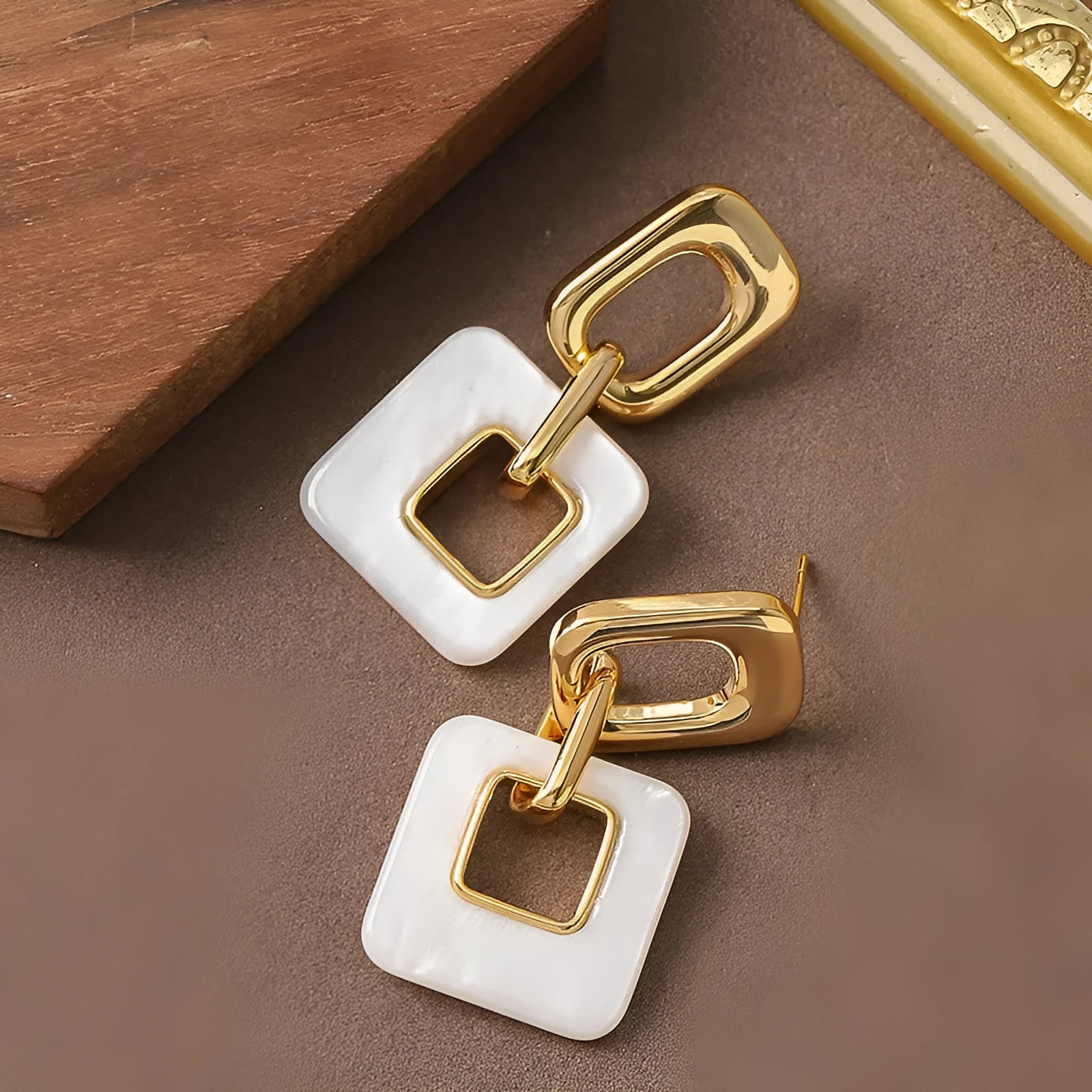 Pair of hollow geometric square copper earrings with chamfered corners in silver tone finish.