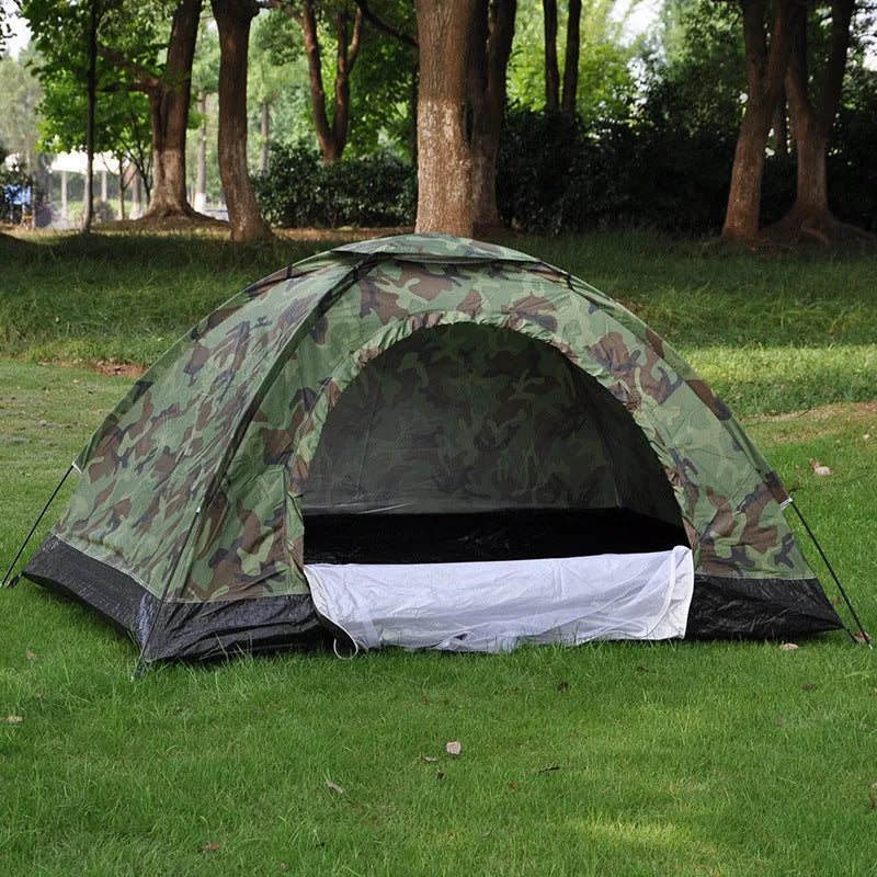 Green camouflage two-person camping tent with fibreglass poles pitched outdoors