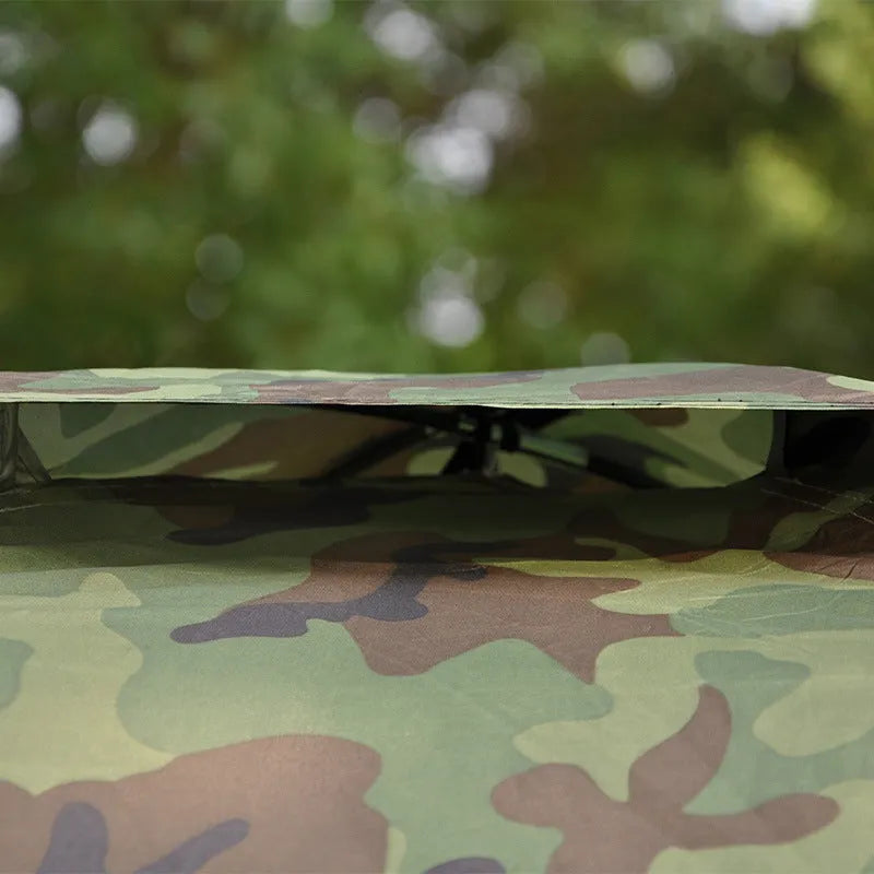 Green camouflage two-person camping tent with fibreglass poles pitched outdoors
