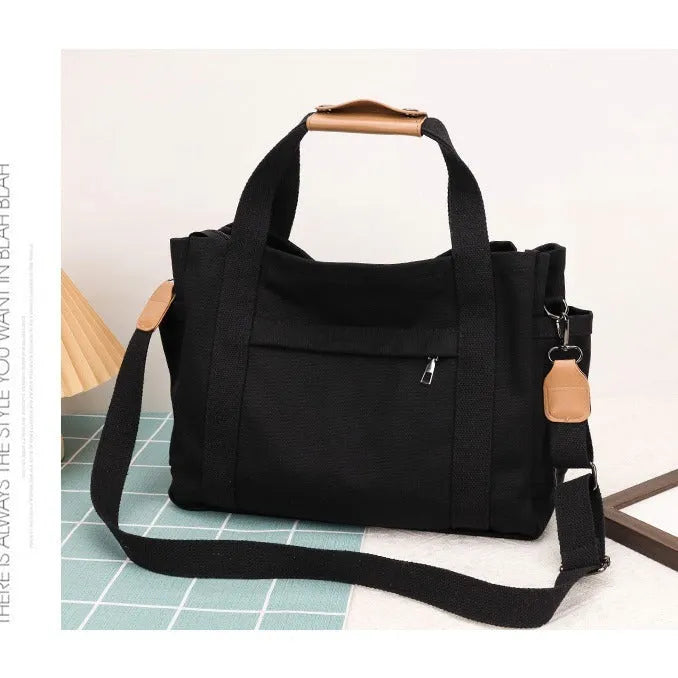 Army green canvas tote bag with open zip sides showing internal laptop and camera pockets.