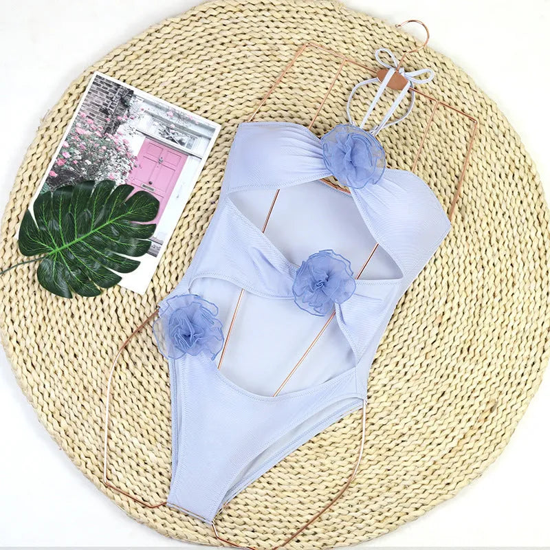 Women's black and blue striped one-piece swimsuit with 3D flower design on the front.