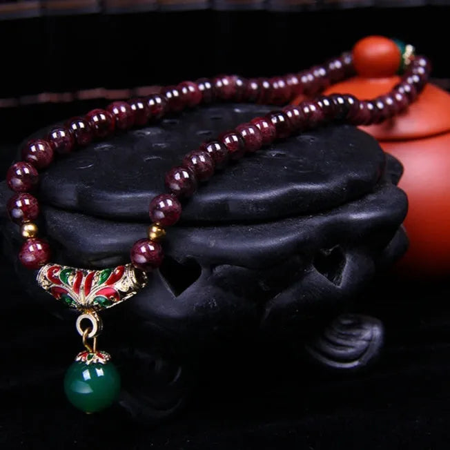 Natural garnet double ring bracelet with a central golden toad charm on an adjustable cord.