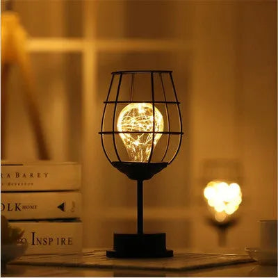 Minimalist hollow wrought iron table lamp in red wine glass style with warm white LED light.
