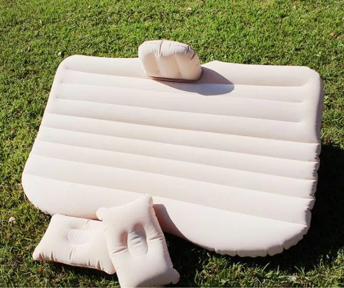 Black inflatable car bed with flocked texture and two pillows, shown inside a car boot.