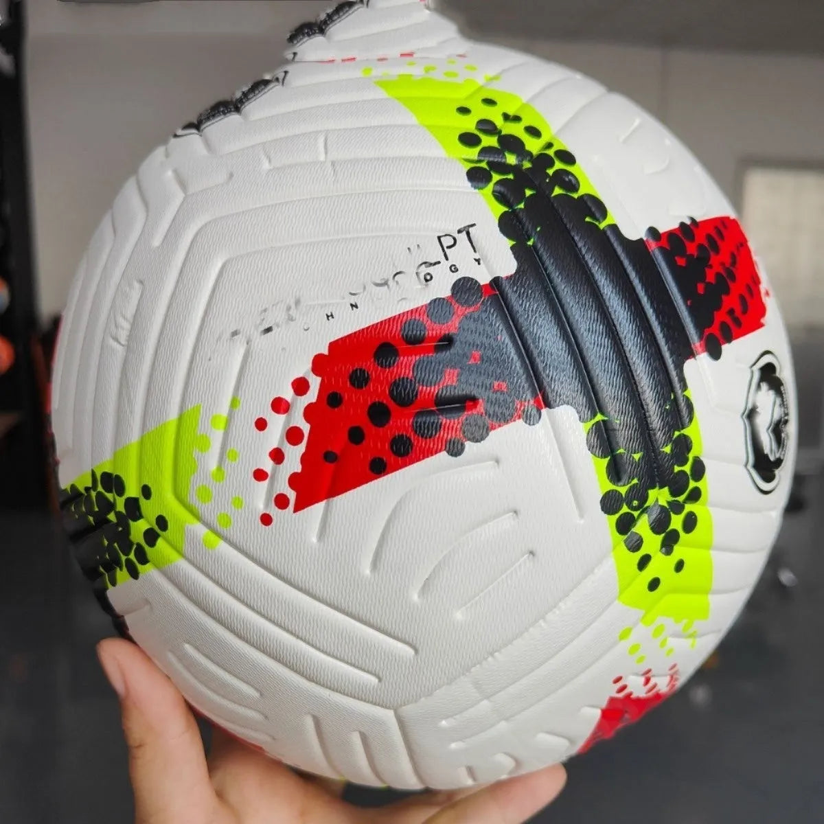 Fluorescent green Size 5 PU football with seamless thermal adhesive patch construction on grass.