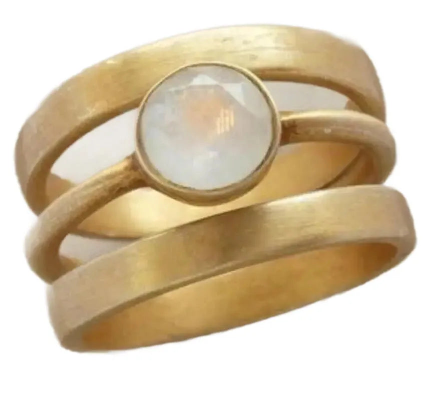 Gold-plated geometric ring with a white chalcedony stone centrepiece on a grey background.