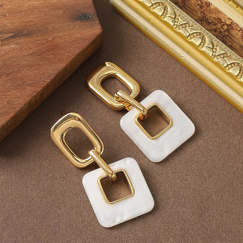 Pair of hollow geometric square copper earrings with chamfered corners in silver tone finish.