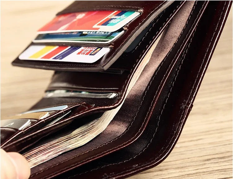 Men's leather wallet open to show internal card slots, cash section, coin pocket, and document holder.