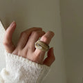 Chinese style irregular wide geometric resin ring in brown or white on display.
