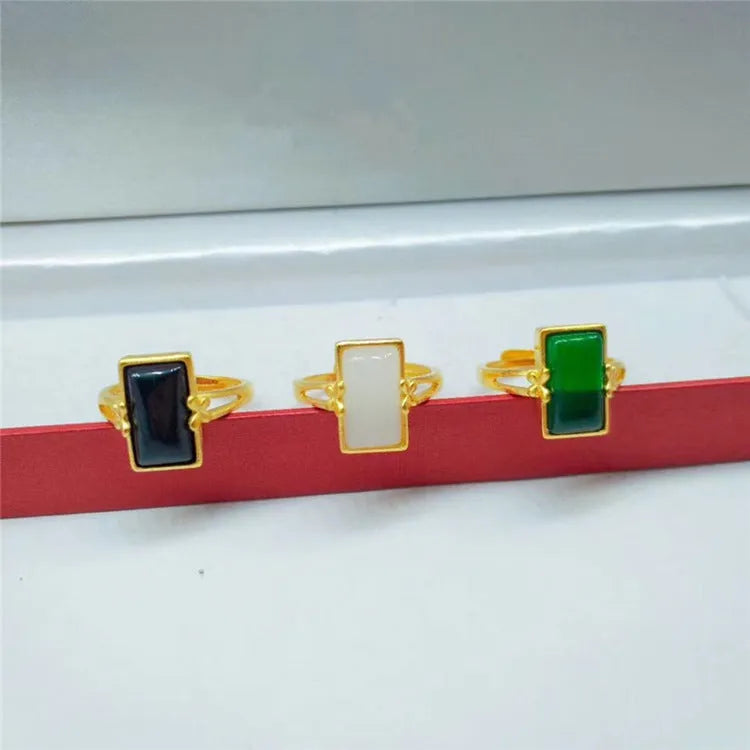 Gold-plated adjustable brass ring with a central inlaid gemstone, shown in black, green, and white colour options.