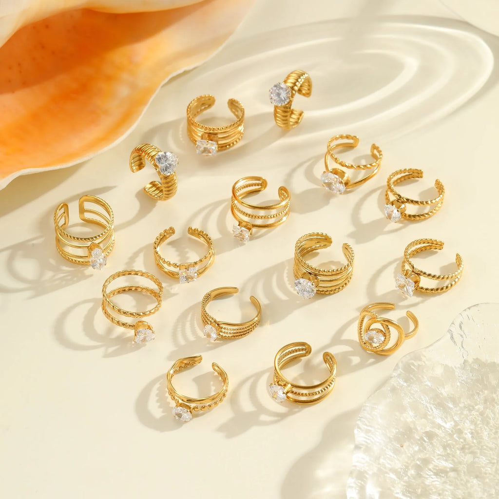 Gold-coloured stainless steel ring with an inlaid zircon stone and geometric heart design on an adjustable open mouth band.