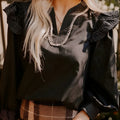 Black women's V-neck blouse with contrast stitching and ruffle detail on long sleeves