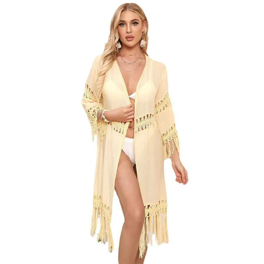 Yellow hand crocheted women's beach cover-up cardigan with tassels on a hanger