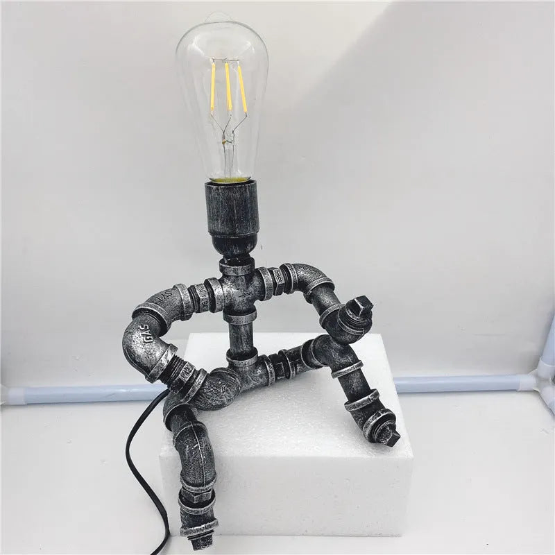 Industrial retro style table lamp made from iron pipes with a robot figure detail, in a vintage finish.