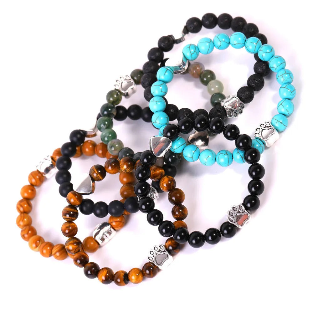Close-up of a tiger's eye and Indian agate bead bracelet with a central geometric dog's paw charm on a wrist.