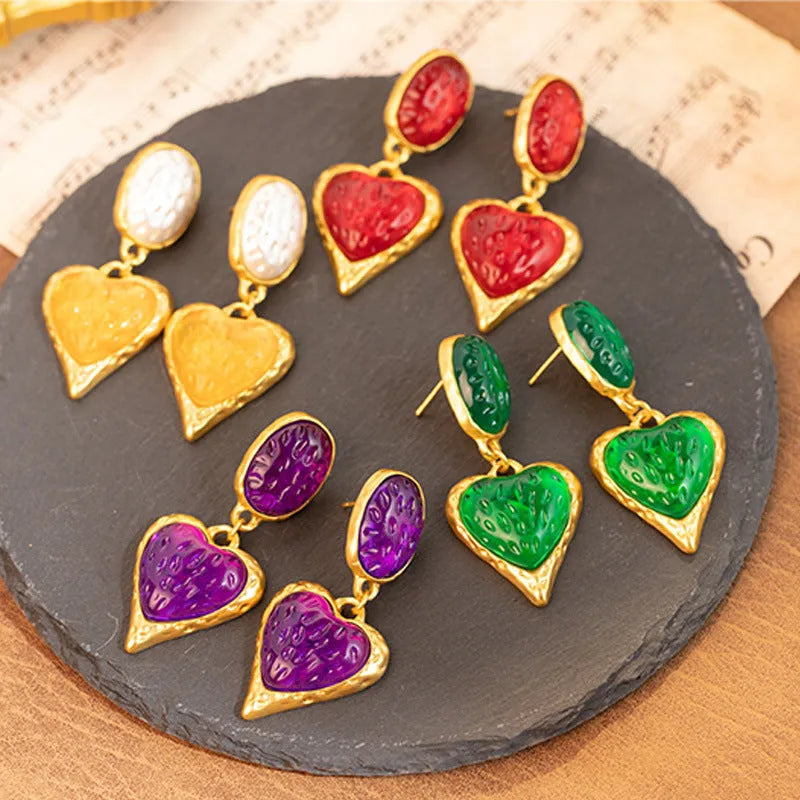 A pair of oval-shaped love heart stud earrings with a pleated surface, shown in one of four colour options.