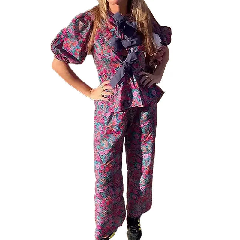 Women's floral print two-piece trouser suit with puff sleeve top and matching trousers.