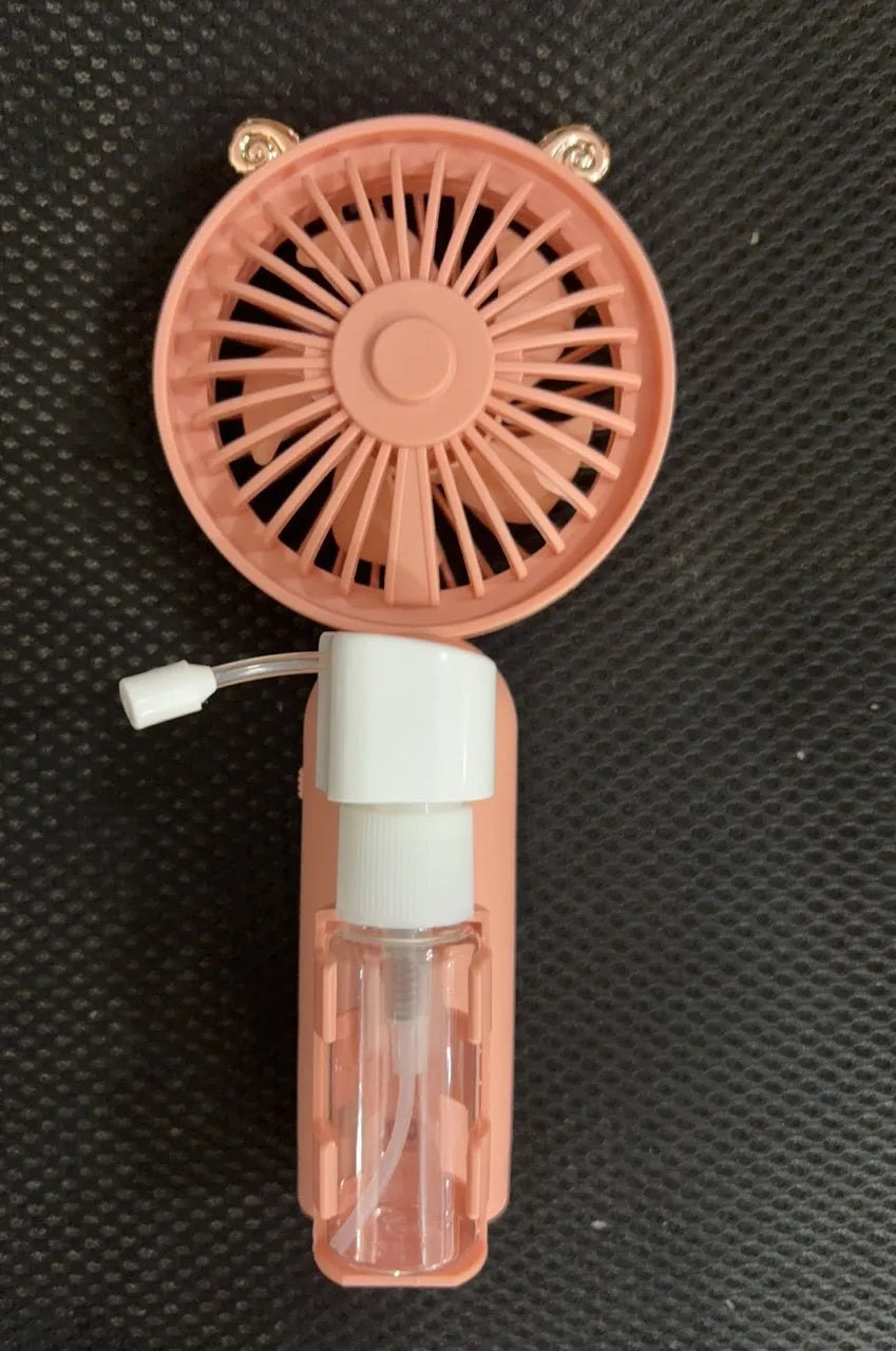 Compact plastic USB-powered desk fan with nozzle, shown in apricot colour on a wooden desk.