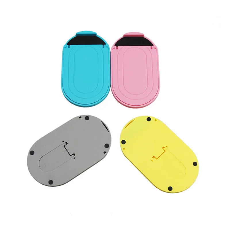 A plastic lazy bracket mobile phone stand on a table, shown in one of six available colours.