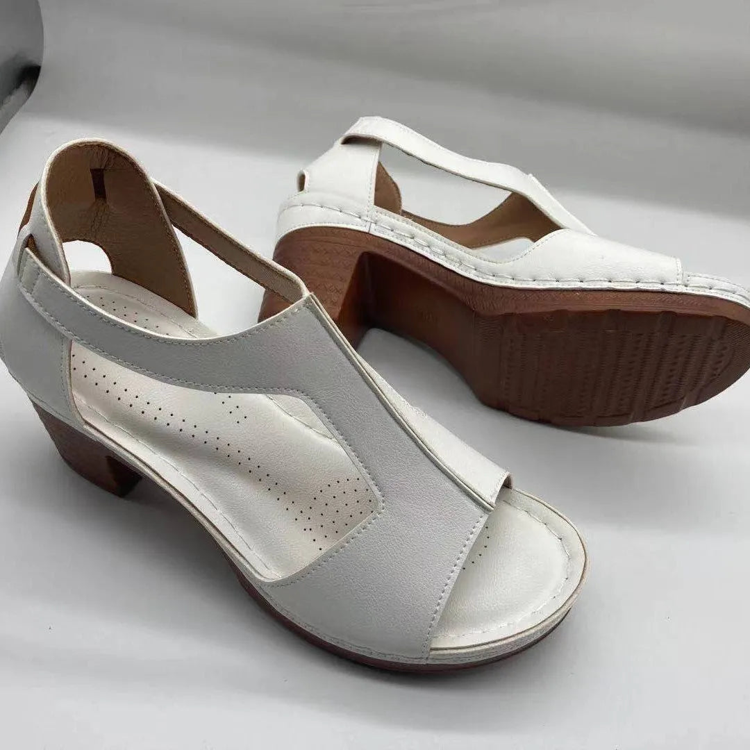 Women's white peep toe wedge sandals with a buckle and low heel on a neutral background.