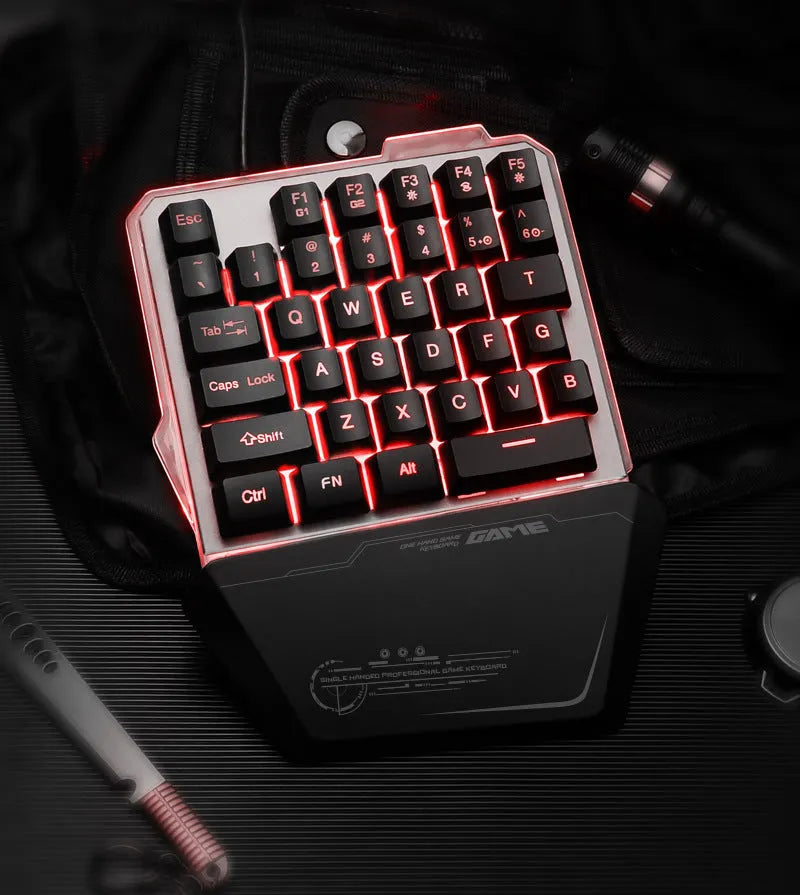 Black one-handed robotic gaming keyboard with RGB backlit keys on a desk.