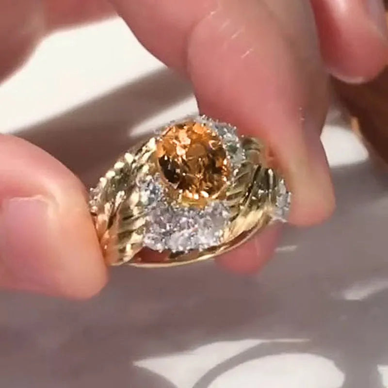 Gold-coloured copper ring with embossed feather pattern and a yellow zircon stone.
