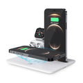 Black desktop wireless charging station with phone on pad, watch in bracket, and headphones on hook.