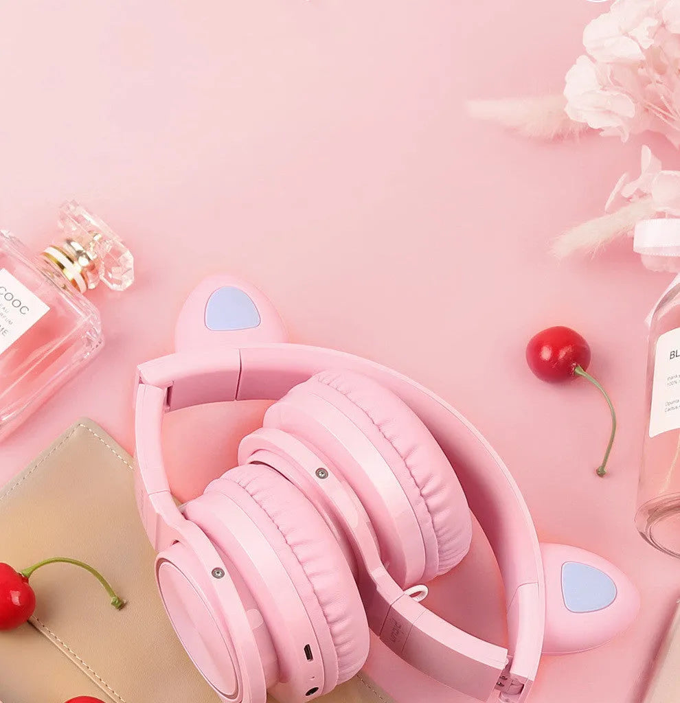 Pink white Luminous Bluetooth over-ear headphones showing protein ear cushions and braided cable.