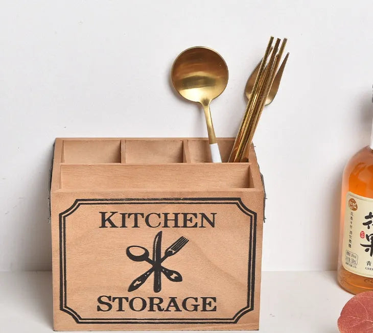 Open-top wooden kitchen storage box with internal grid divider for organising utensils.