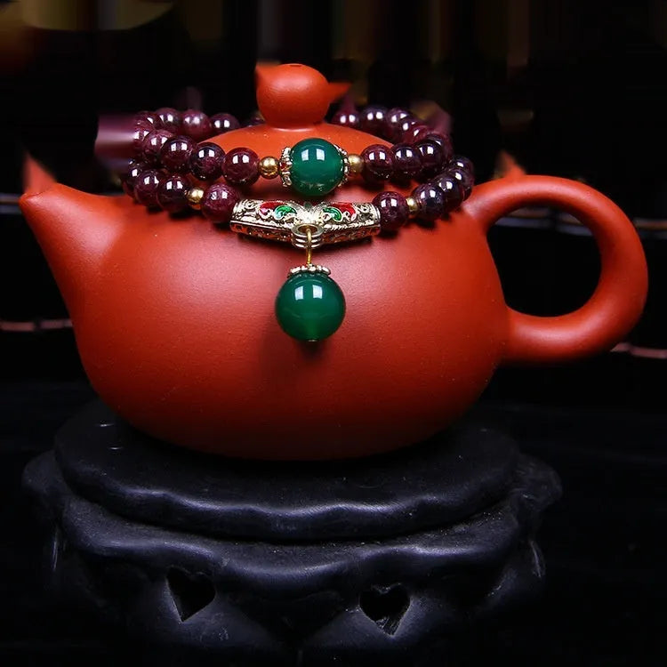Natural garnet double ring bracelet with a central golden toad charm on an adjustable cord.