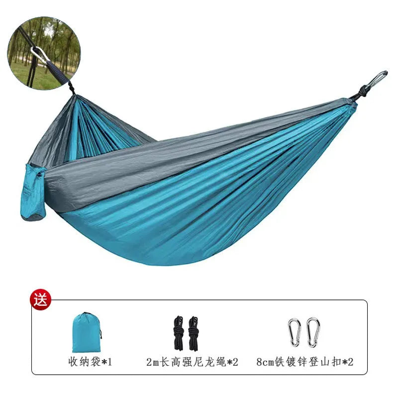 Blue parachute nylon camping hammock hung between two trees showing its full 270 cm length.