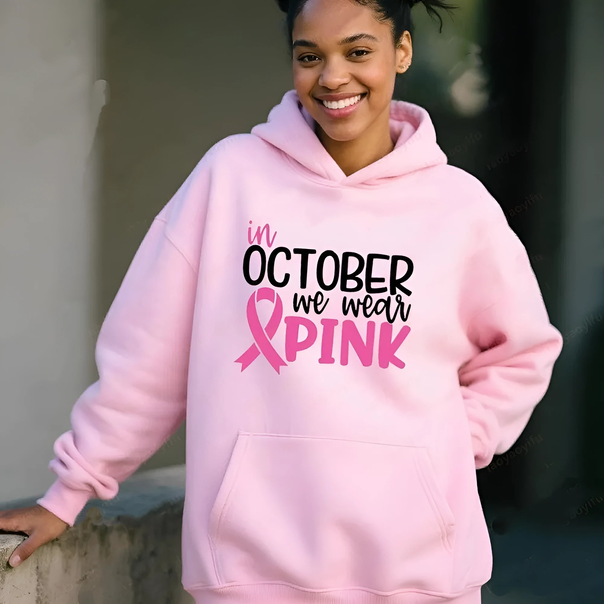 Women's pink pullover hoodie with 'In October We Wear Pink' and 'I'm A Survivor' retro hot stamping design and side seam pockets.