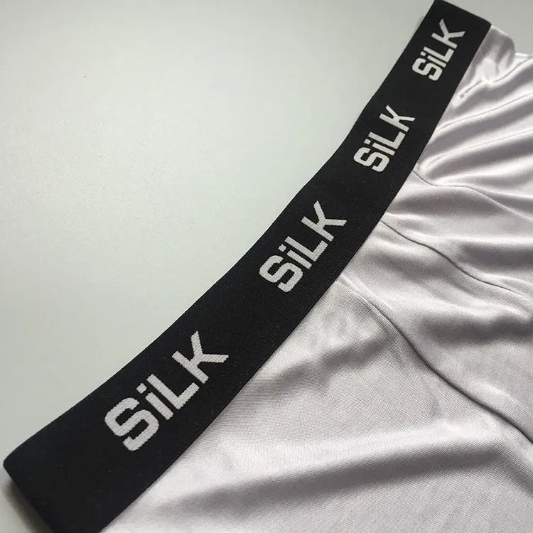 Man wearing loose-fitting mid-waist silk shorts in navy blue, silver grey, or skin colour.