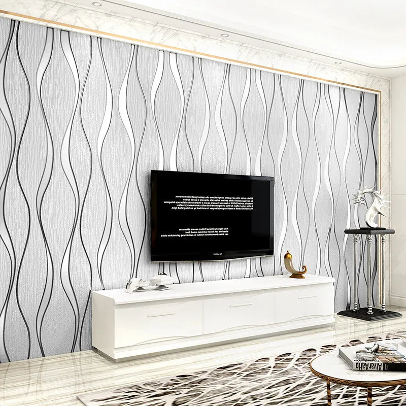 Roll of grey 3D curve stripe textured velvet wallpaper against a wall.