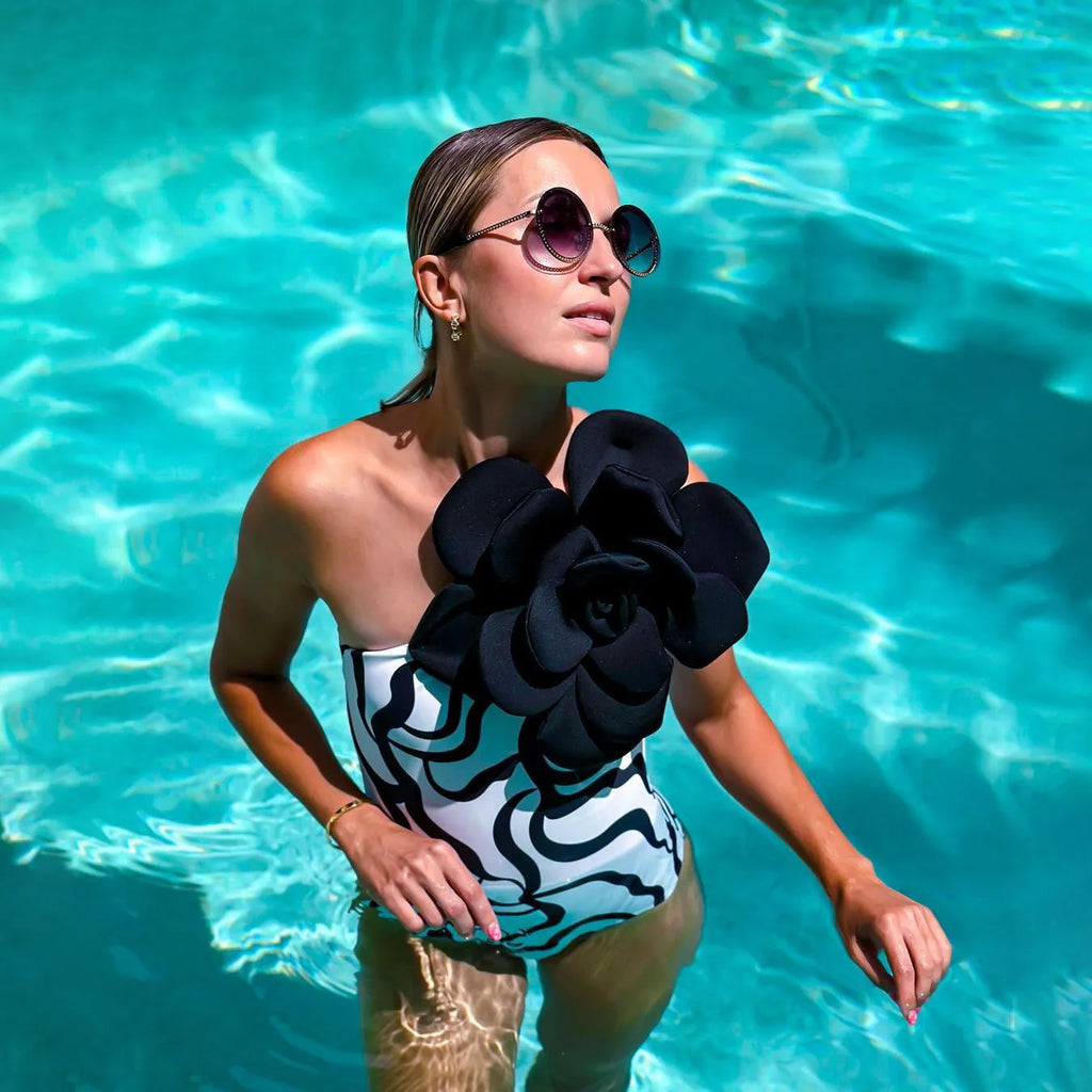 Women's black one-piece swimsuit with three-dimensional white floral pattern, showcasing European/American fit.
