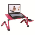 Red folding metal computer desk with extended legs and a mouse board, set up on a bed.