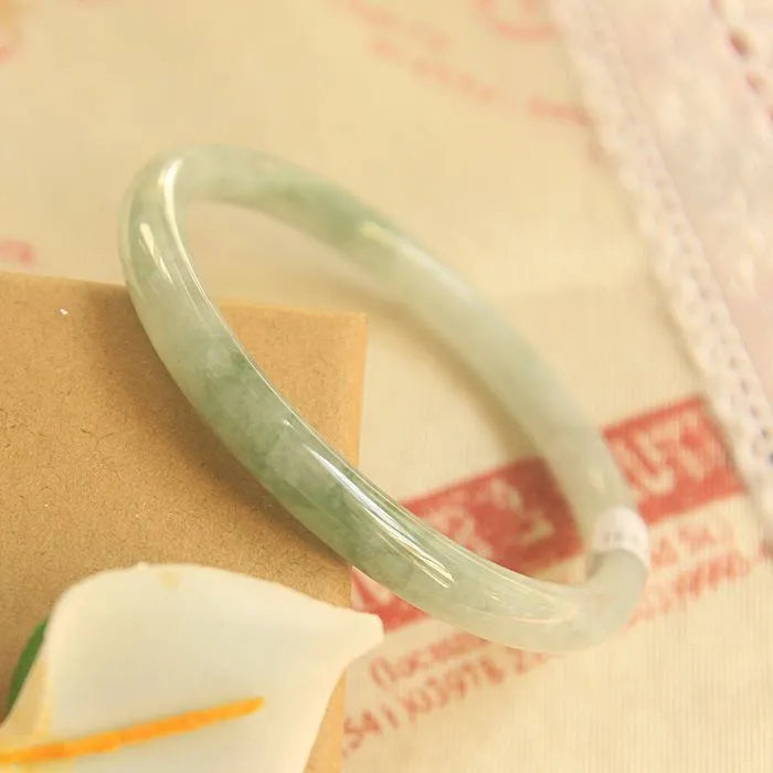 Green handmade geometric jade waxy bracelet with a 10mm bead on a black background.