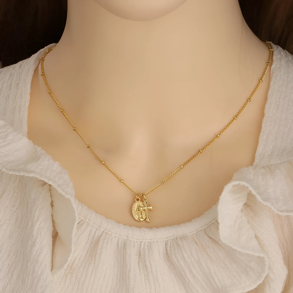 Gold-coloured geometric cross pendant necklace with a Virgin Mary ornament, on a chain.