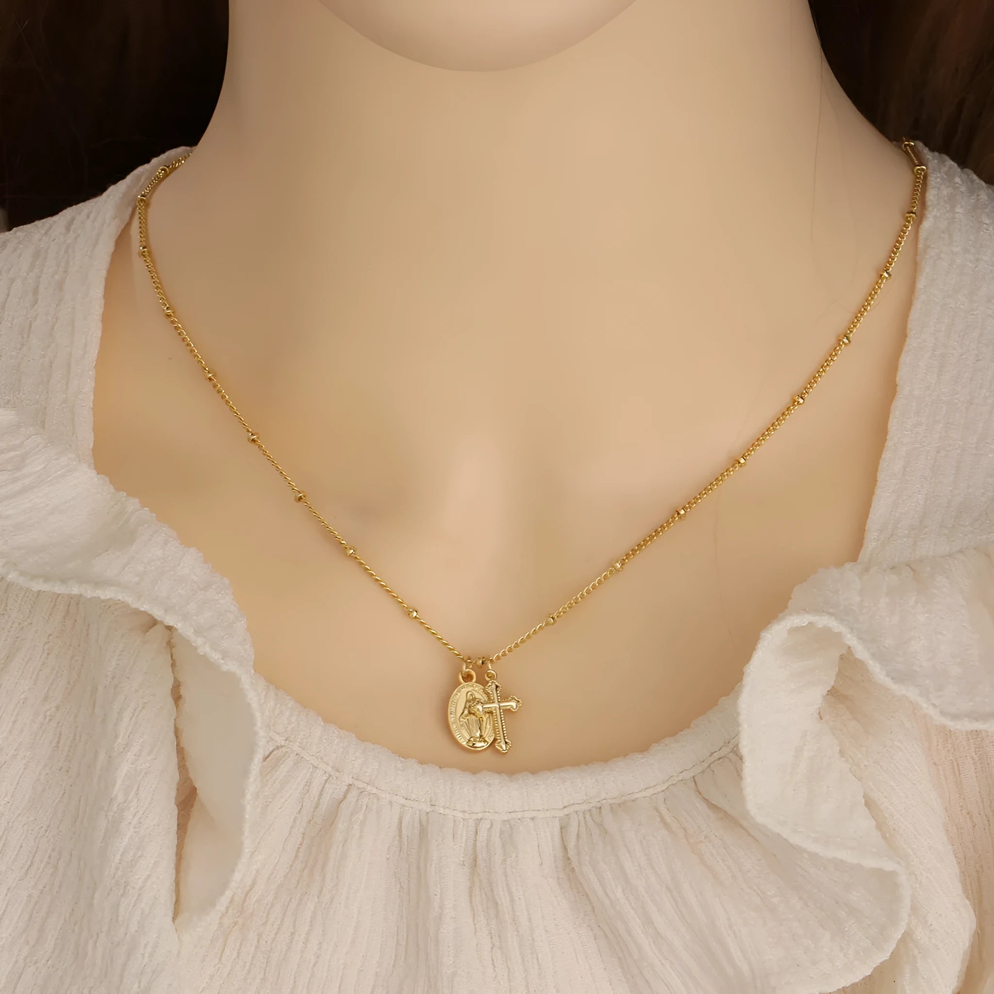 Gold-coloured geometric cross pendant necklace with a Virgin Mary ornament, on a chain.