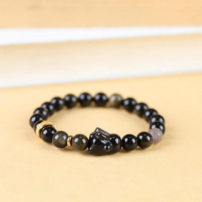 Handmade Chinese style bracelet with lying rabbit charm, grey agate bead, and brass on a black background.