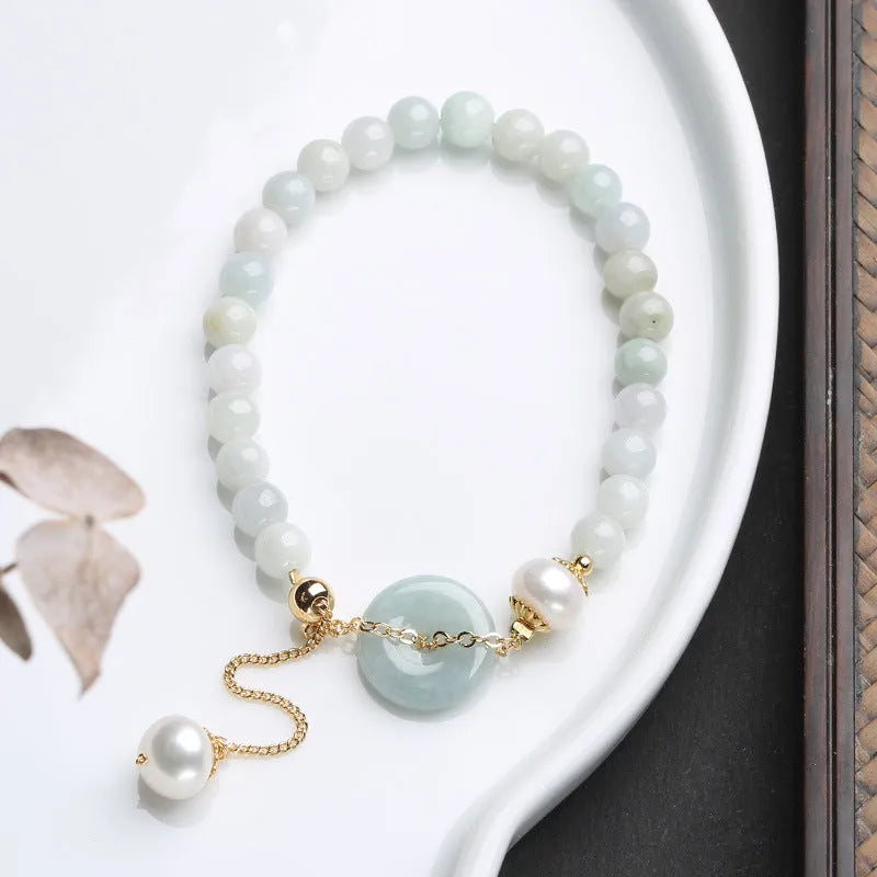 Natural emerald green jade round pendant on a women's bracelet with a geometric peace buckle.