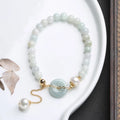 Natural emerald green jade round pendant on a women's bracelet with a geometric peace buckle.