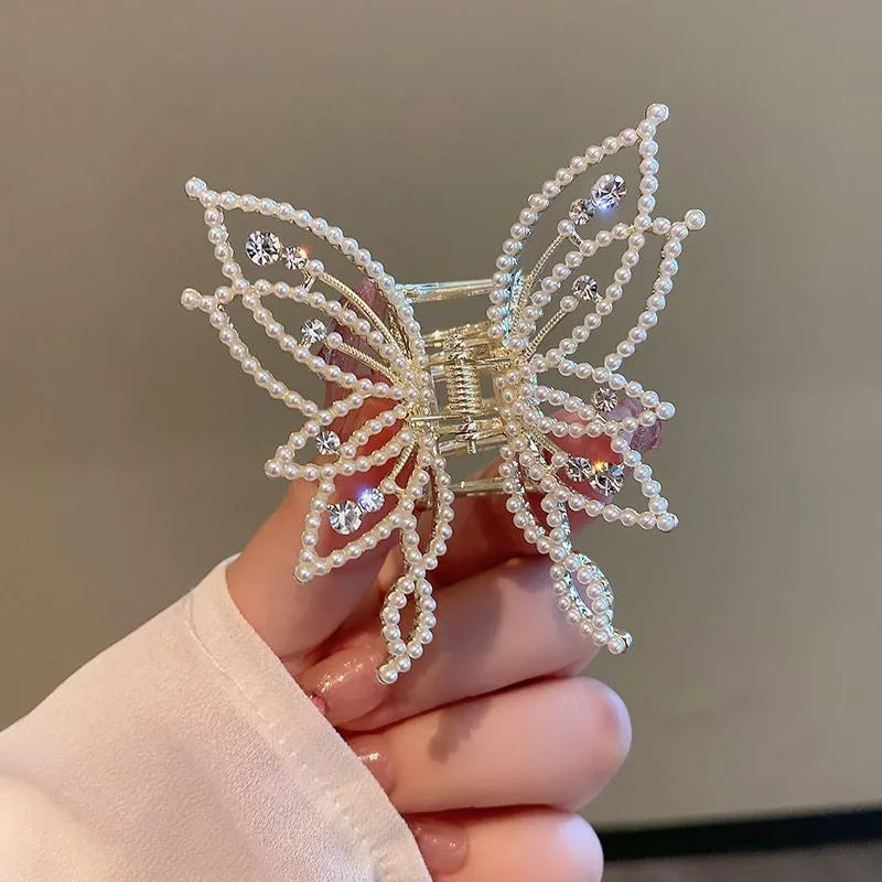 Butterfly-shaped alloy hair clip with electroplated finish in pearl or rhinestone style.