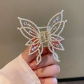 Butterfly-shaped alloy hair clip with electroplated finish in pearl or rhinestone style.